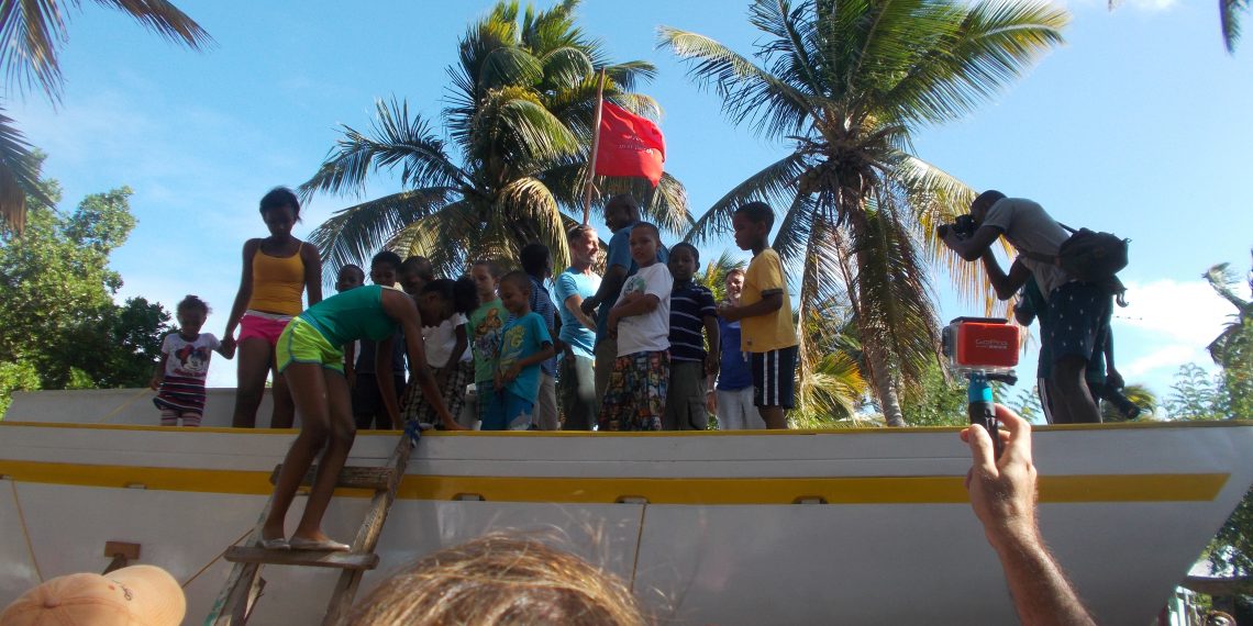 A crowd gathers for the blessing of the boat. The people onboard are family members of the builders, the owner, and others with a special connection.